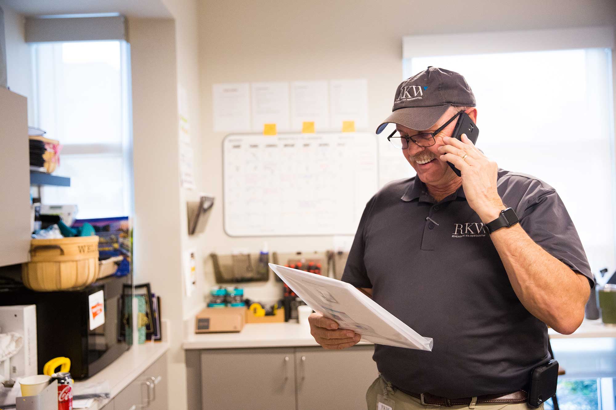 a man holding a paper and talking on a cell phone