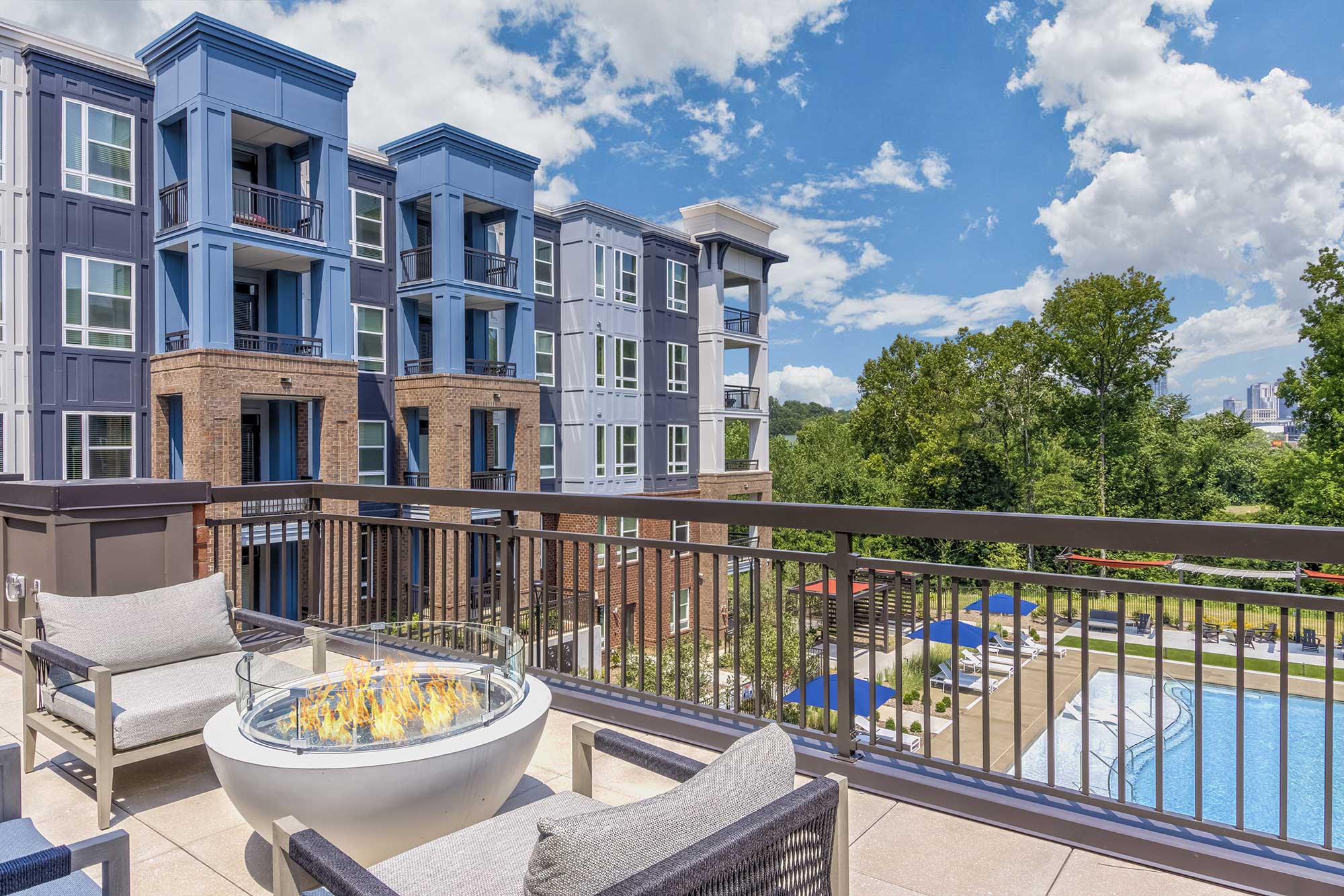 a balcony with a fire pit and a pool in the background