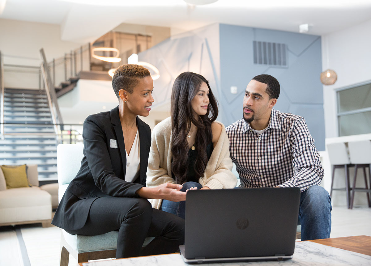 a group of people sitting on a couch looking at a laptop