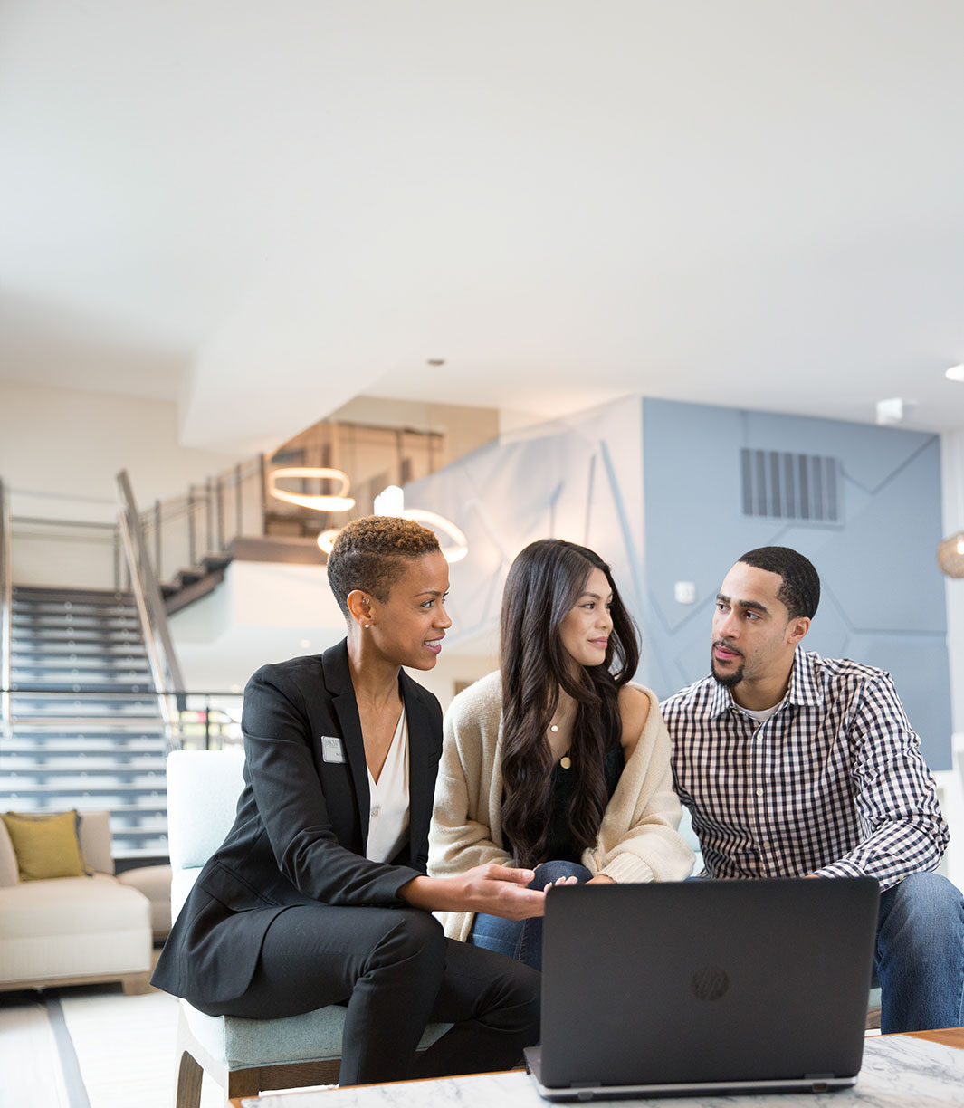 a group of people sitting on a couch looking at a laptop