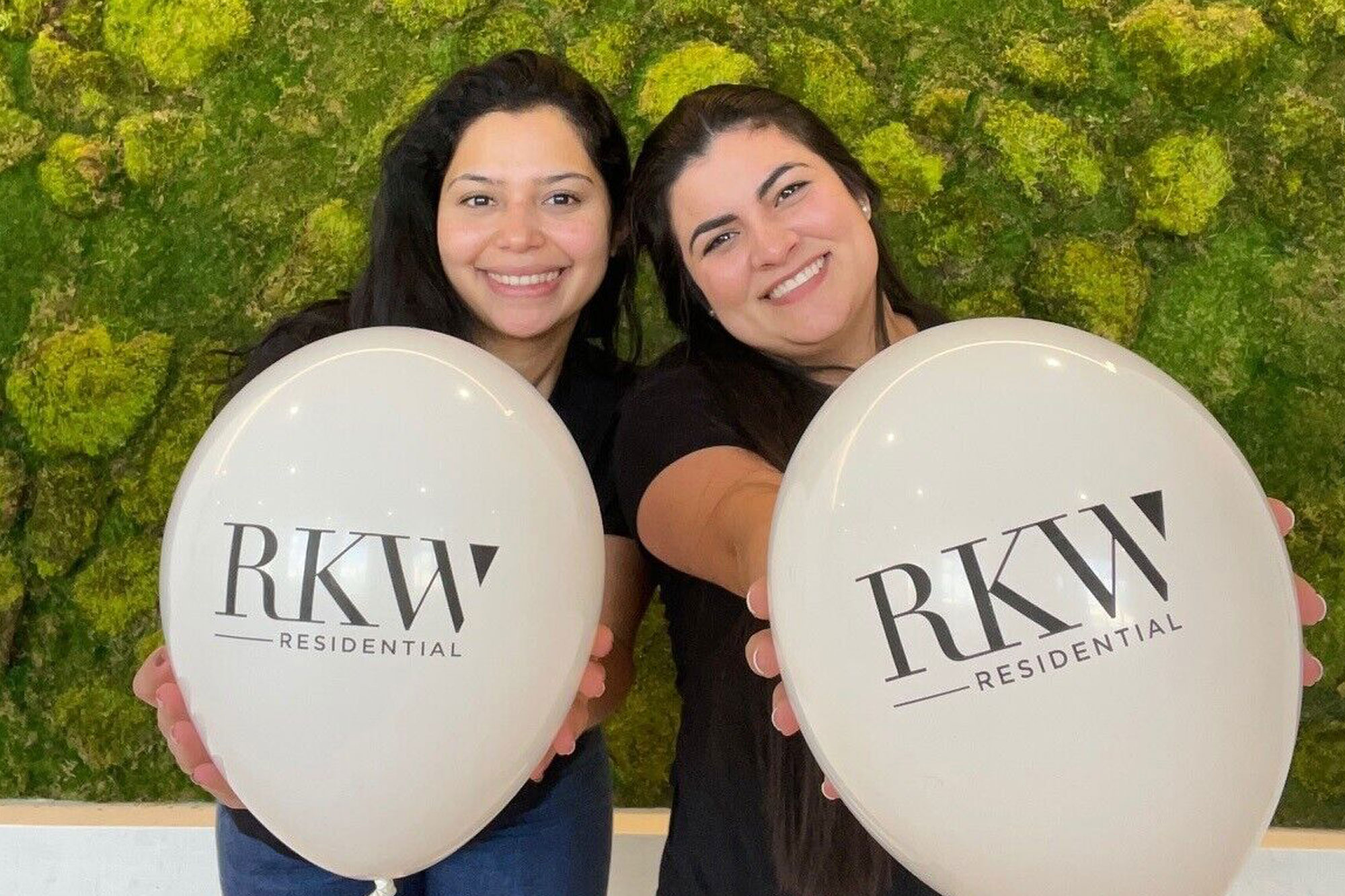 two women holding balloons in front of a green wall