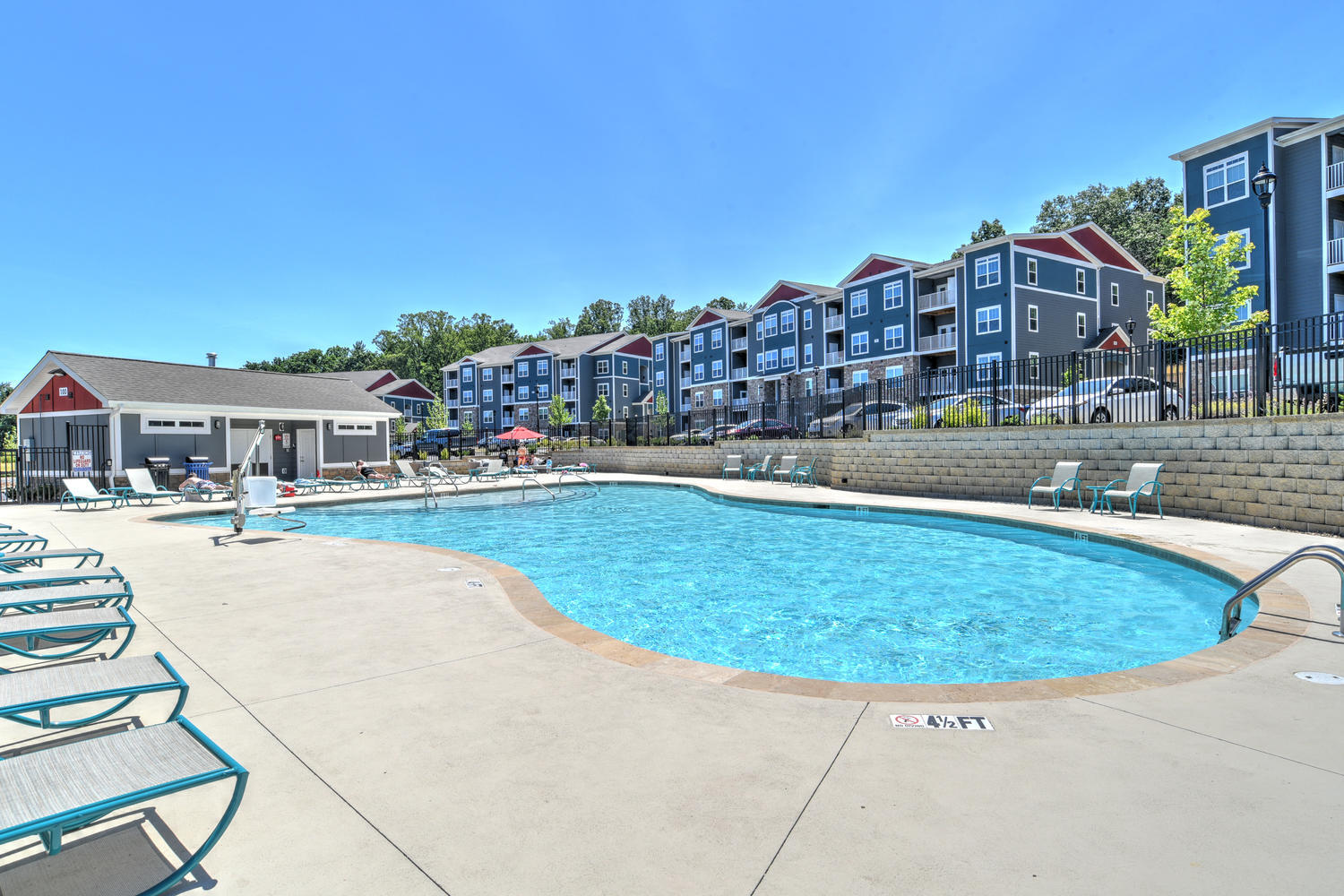 a pool with chairs and a building in the background