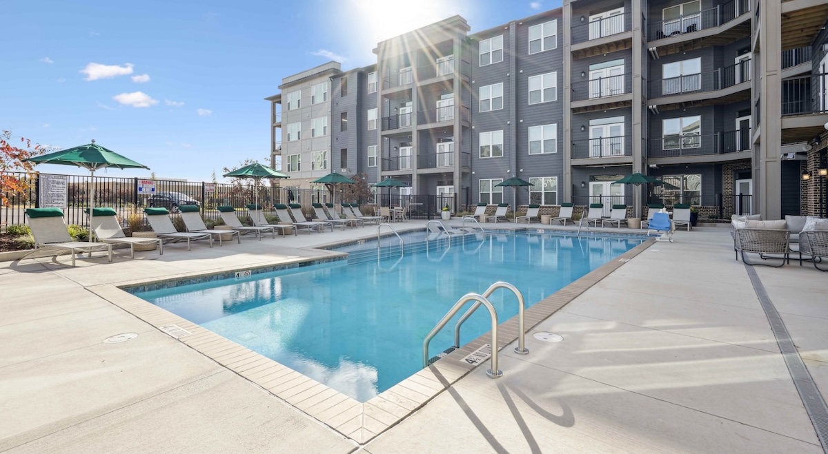 a swimming pool with chairs and a building